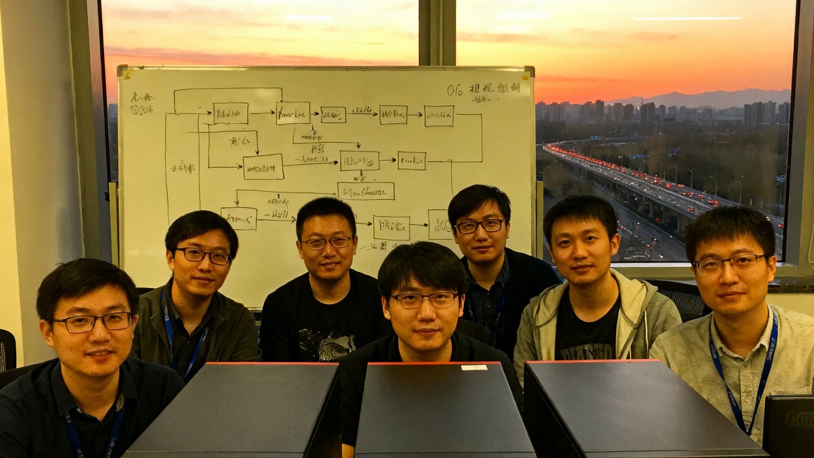 2016年OG视讯初创团队在共享办公室里的合影，七位工程师围坐在三台服务器前，白板上画满了视频编码算法流程图，窗外是北京东五环的黄昏天际线。